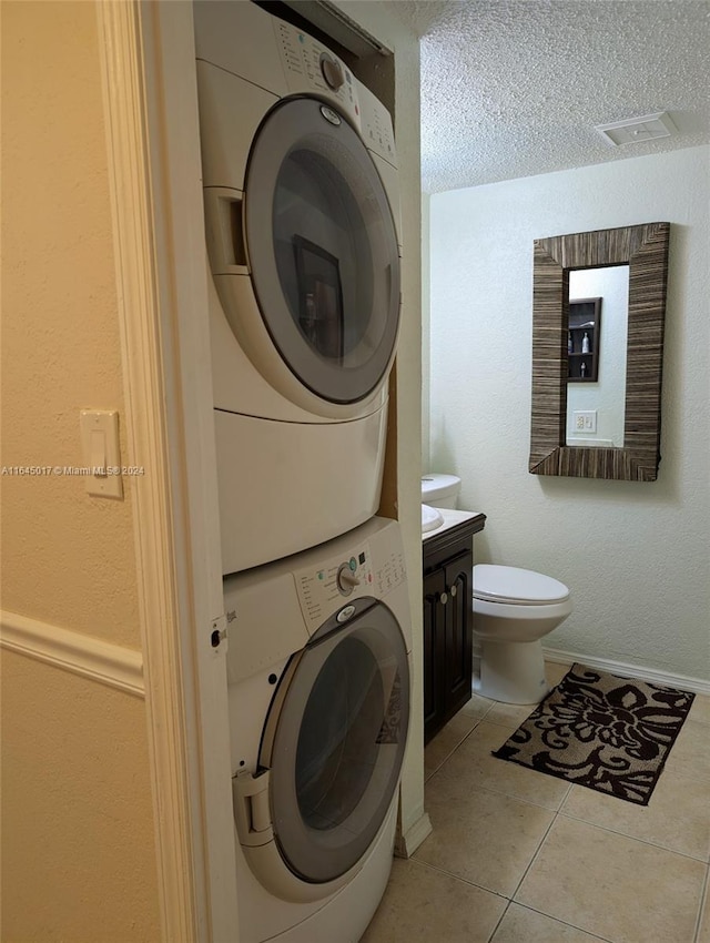 laundry room with stacked washer and dryer, laundry area, light tile patterned flooring, and baseboards