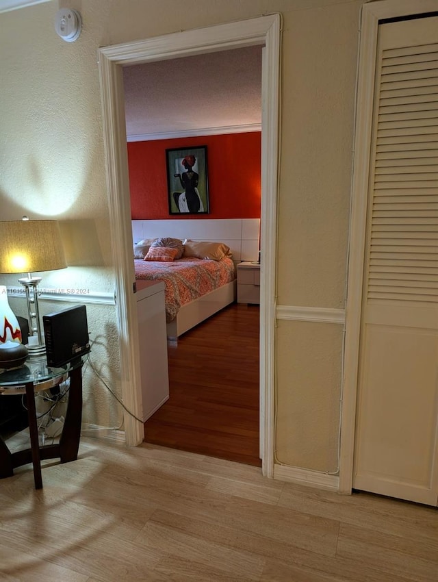 bedroom with light wood-style floors and a textured wall