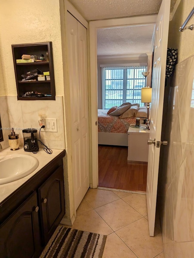 bathroom featuring connected bathroom, tile patterned flooring, a textured ceiling, vanity, and a closet