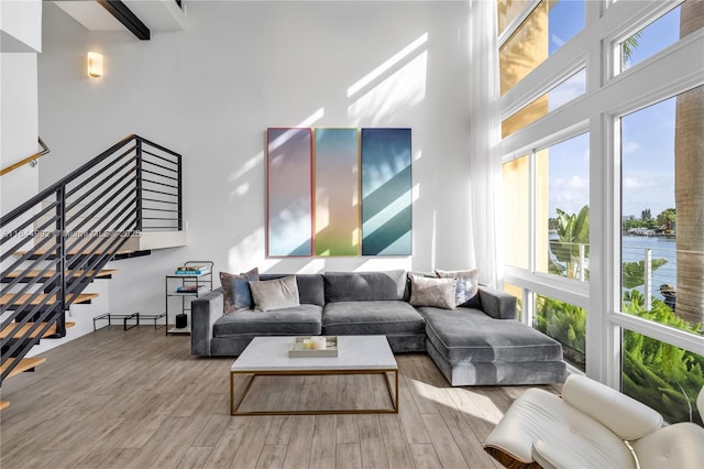 living room featuring beam ceiling, light hardwood / wood-style flooring, and a water view