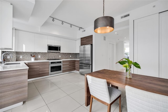 kitchen with sink, hanging light fixtures, appliances with stainless steel finishes, decorative backsplash, and white cabinets