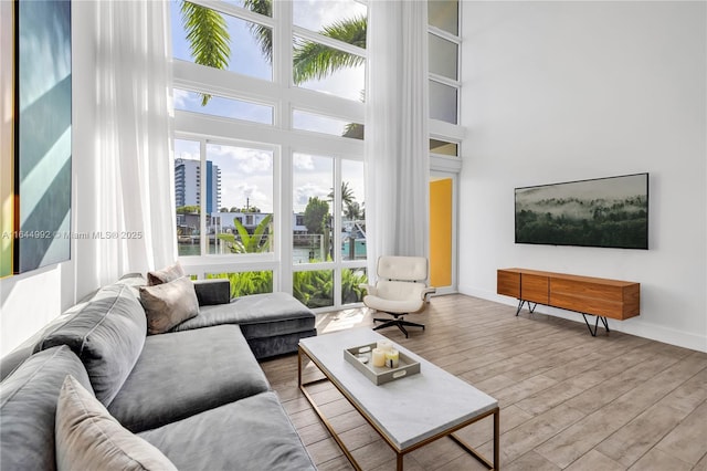 living room featuring a high ceiling, plenty of natural light, and light hardwood / wood-style flooring