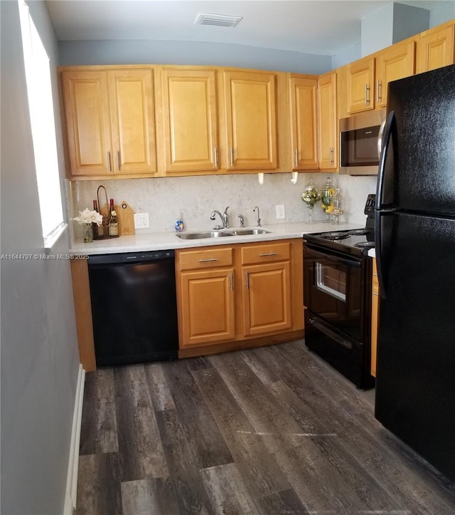 kitchen featuring visible vents, dark wood finished floors, light countertops, black appliances, and a sink