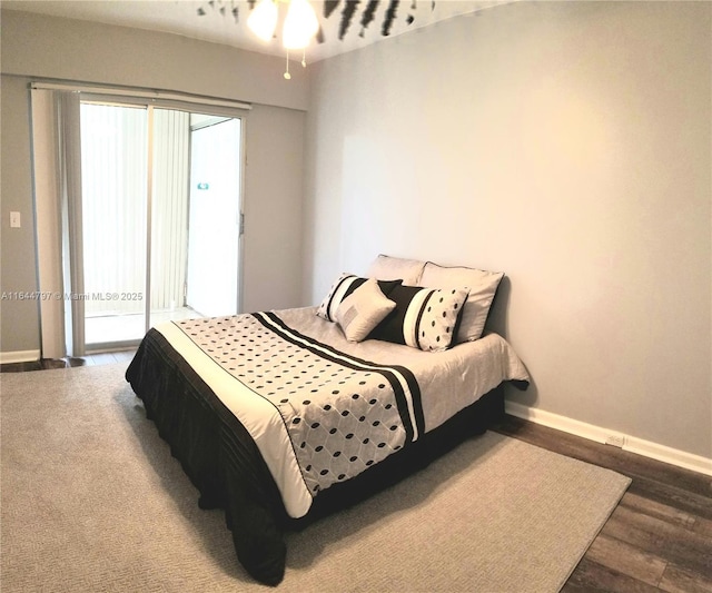 bedroom featuring access to exterior, baseboards, and wood finished floors