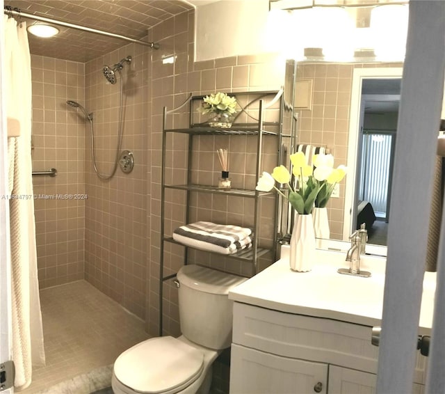 bathroom with tile walls, toilet, vanity, and curtained shower