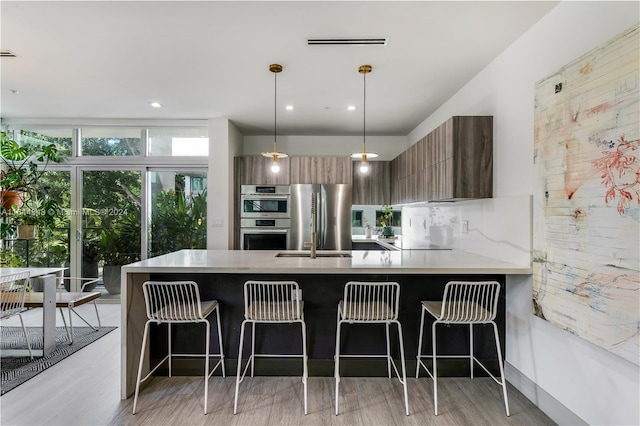 kitchen with appliances with stainless steel finishes, light hardwood / wood-style flooring, a breakfast bar, and tasteful backsplash