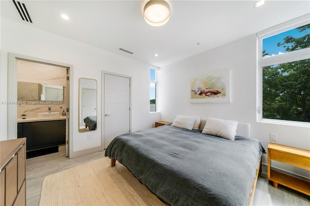 bedroom featuring light wood-type flooring and ensuite bath