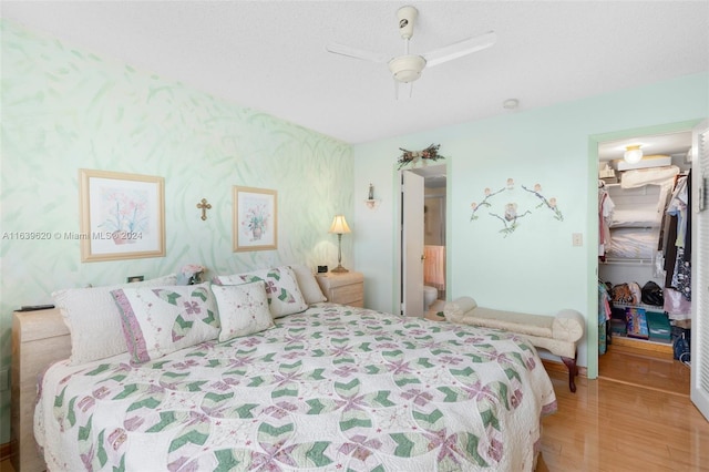 bedroom with a closet, ceiling fan, hardwood / wood-style flooring, a walk in closet, and connected bathroom