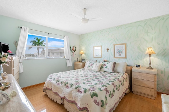 bedroom with ceiling fan, light hardwood / wood-style floors, and a textured ceiling