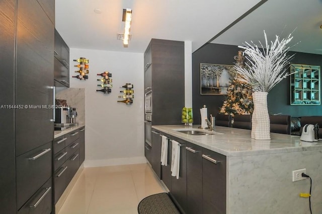 kitchen with oven, light tile patterned floors, sink, and light stone countertops