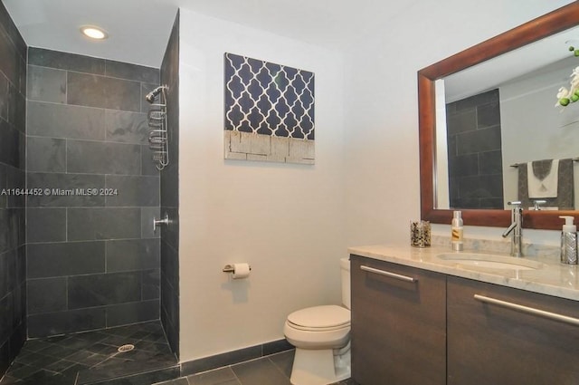 bathroom featuring tiled shower, toilet, and vanity