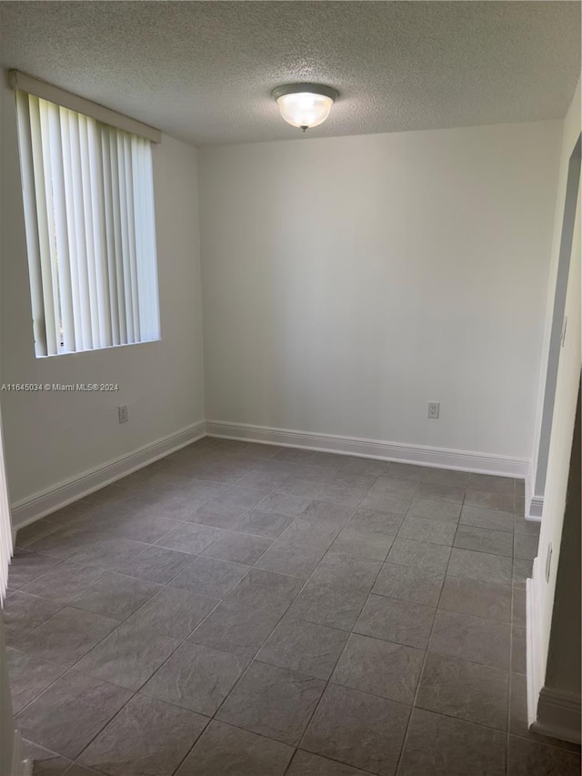 tiled empty room featuring a textured ceiling