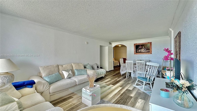 living room with a textured ceiling, wood-type flooring, and crown molding