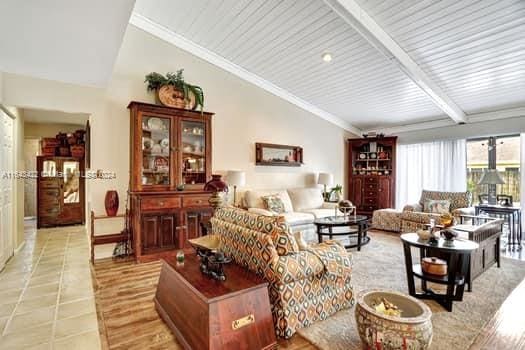 living room with light tile patterned floors and vaulted ceiling with beams