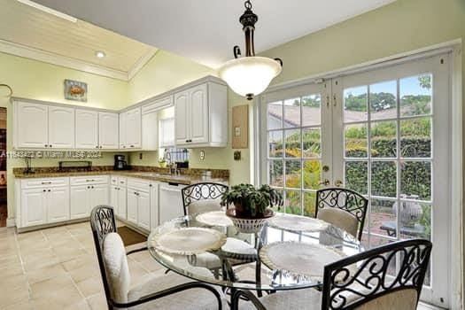 kitchen featuring dishwasher, pendant lighting, ornamental molding, white cabinets, and light tile patterned flooring