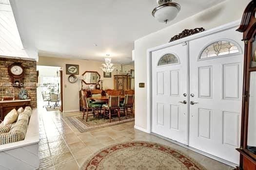 entrance foyer featuring brick wall, a notable chandelier, and tile patterned floors