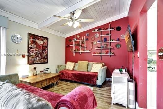 living room featuring wood-type flooring, vaulted ceiling with beams, crown molding, and ceiling fan