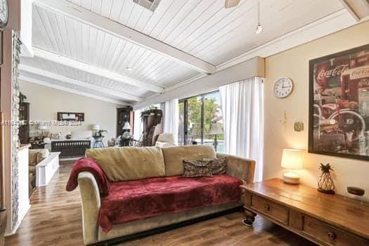 living room featuring ceiling fan, hardwood / wood-style flooring, and lofted ceiling with beams