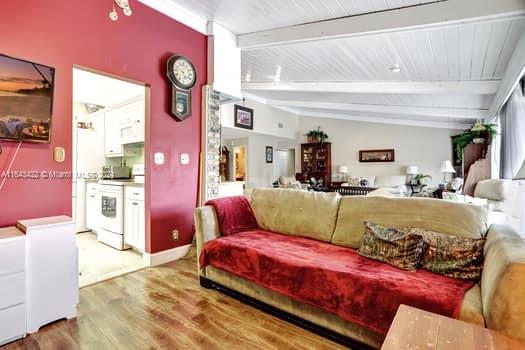 living room featuring wood-type flooring and vaulted ceiling with beams