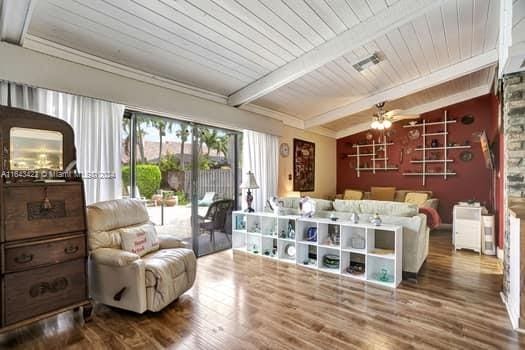 living area with ceiling fan, hardwood / wood-style floors, wooden ceiling, and vaulted ceiling with beams