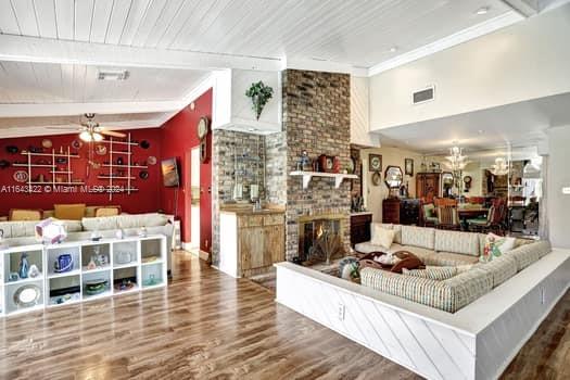 living room featuring ceiling fan, hardwood / wood-style floors, vaulted ceiling with beams, and a fireplace