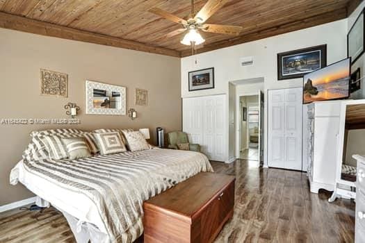 bedroom with ceiling fan, dark hardwood / wood-style floors, and wooden ceiling