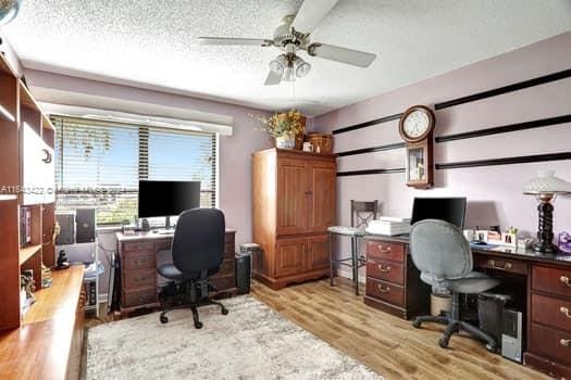 office area featuring light wood-type flooring, a textured ceiling, and ceiling fan