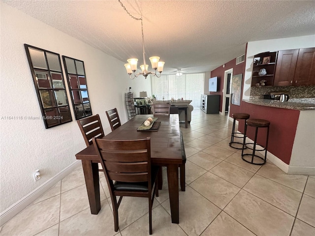 tiled dining room featuring ceiling fan with notable chandelier and a textured ceiling