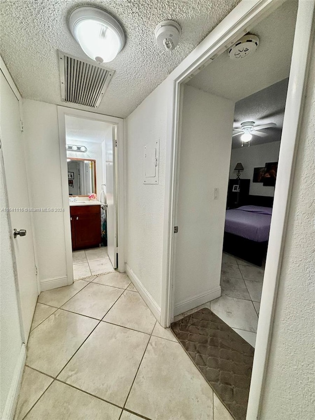 hall featuring a textured ceiling and light tile patterned floors