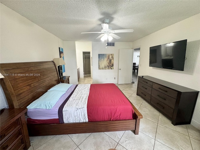 tiled bedroom with ceiling fan, a textured ceiling, and ensuite bathroom