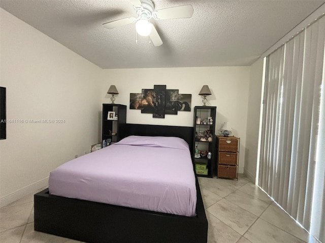 tiled bedroom with ceiling fan and a textured ceiling