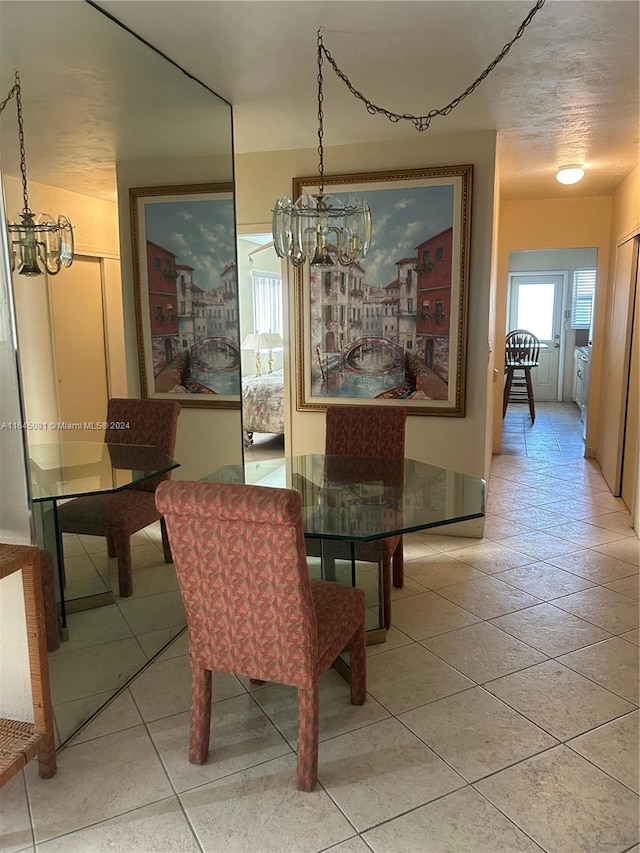 dining space with tile patterned floors, a textured ceiling, and an inviting chandelier