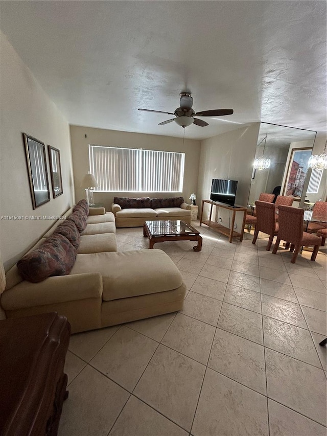 tiled living room featuring ceiling fan with notable chandelier and a textured ceiling