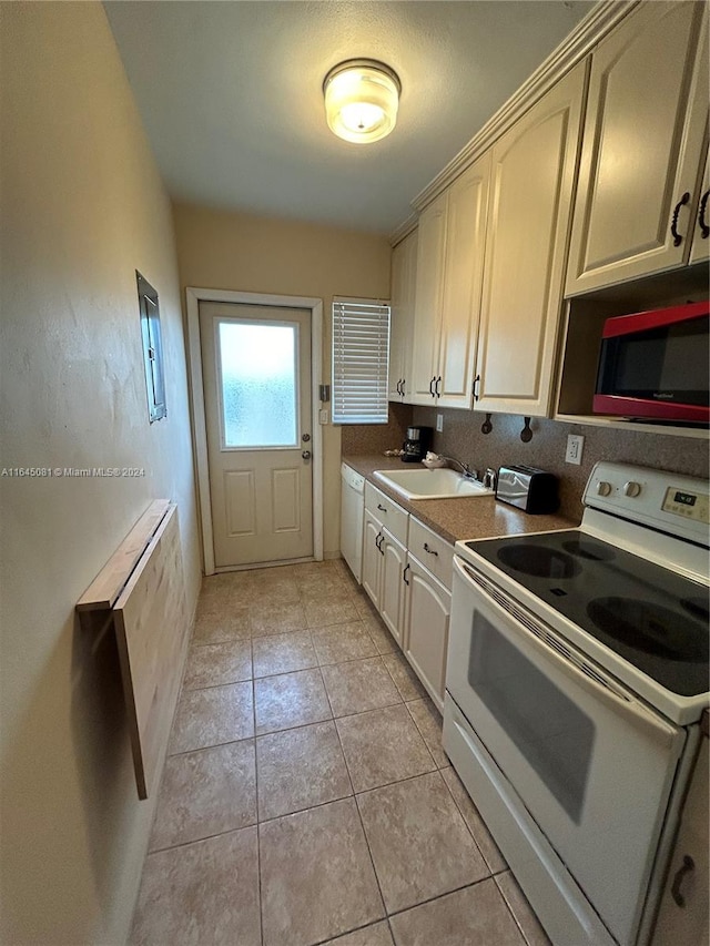 kitchen with light tile patterned flooring, cream cabinets, white appliances, and sink