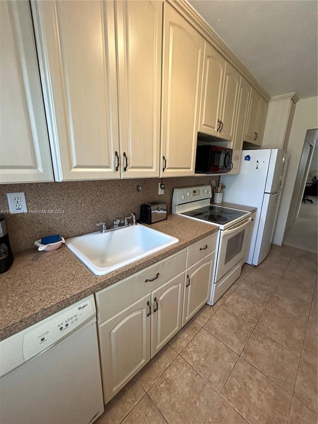 kitchen featuring light tile patterned floors, white appliances, cream cabinets, and sink