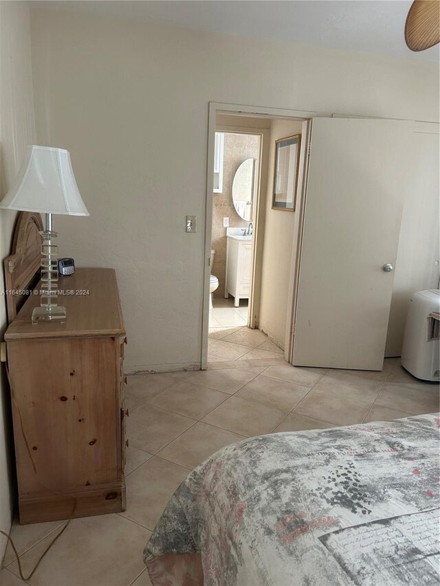 bedroom with ensuite bathroom, light tile patterned flooring, and washer / dryer