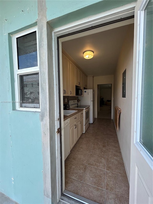 kitchen featuring electric panel, light tile patterned floors, white appliances, and cream cabinetry