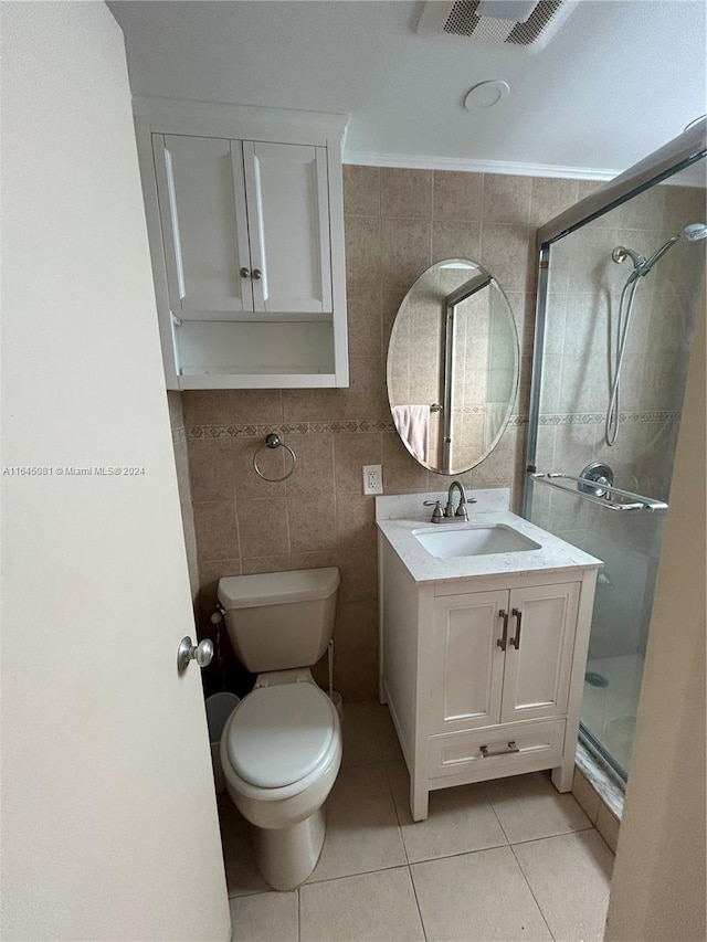 bathroom with tile patterned floors, vanity, a shower with shower door, and tile walls