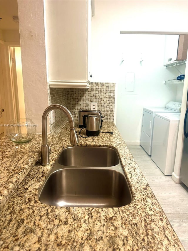 kitchen with light hardwood / wood-style flooring, light stone counters, white cabinetry, sink, and washer and clothes dryer