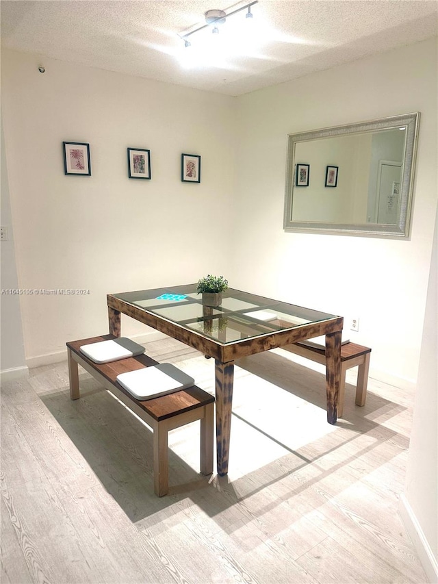 unfurnished dining area with hardwood / wood-style floors, rail lighting, and a textured ceiling