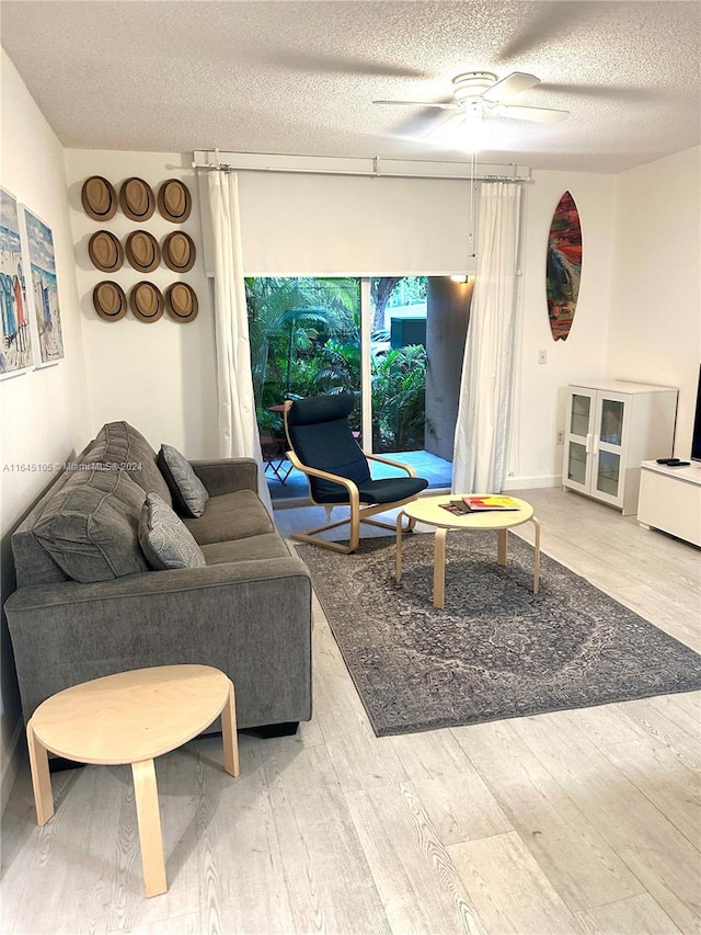 living room featuring a textured ceiling, light hardwood / wood-style flooring, and ceiling fan