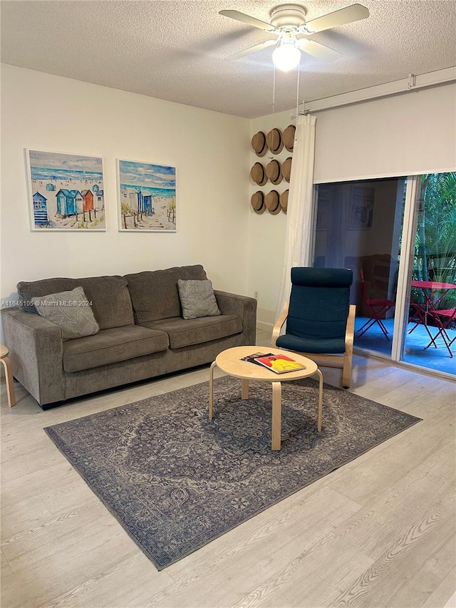 living room featuring a textured ceiling, light hardwood / wood-style flooring, and ceiling fan