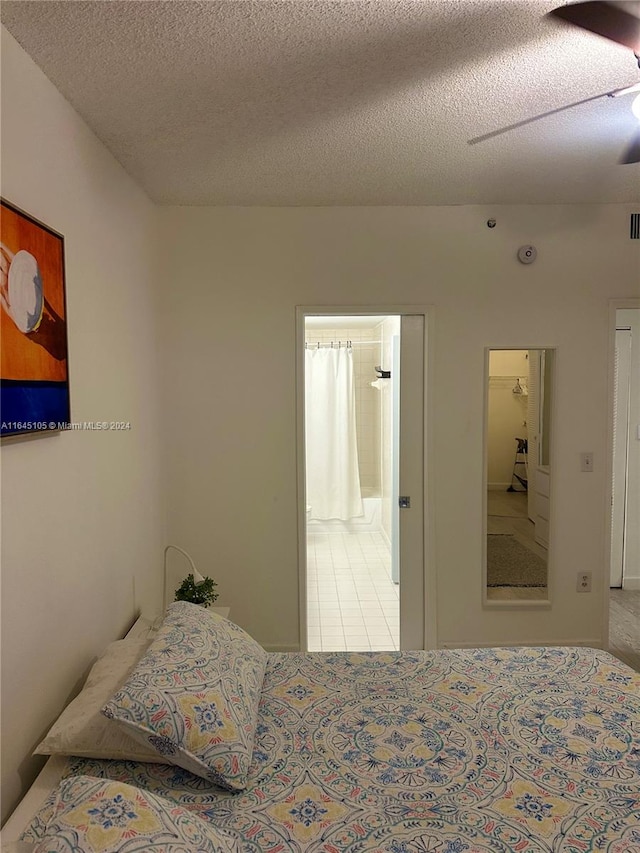 bedroom with ceiling fan, connected bathroom, and a textured ceiling