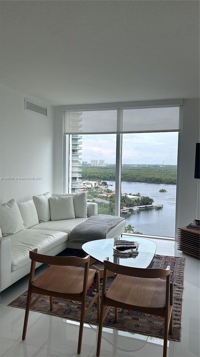 tiled living room with floor to ceiling windows and a water view