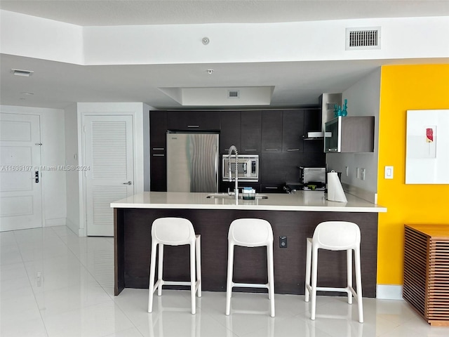 kitchen with light tile patterned floors, stainless steel appliances, kitchen peninsula, and a breakfast bar