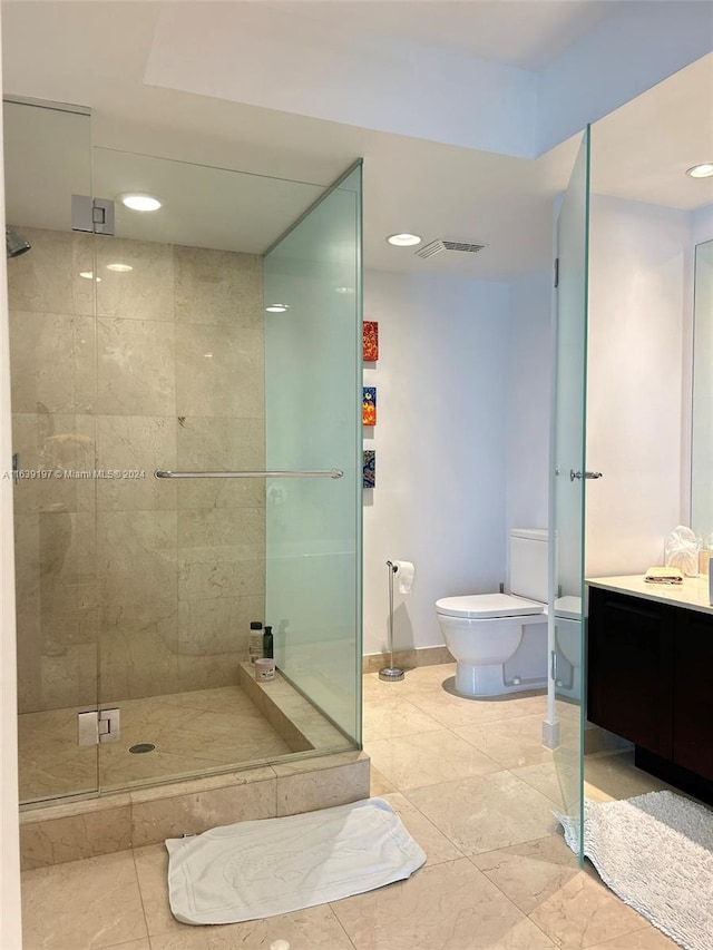 bathroom with tile patterned floors, a shower with shower door, vanity, and toilet