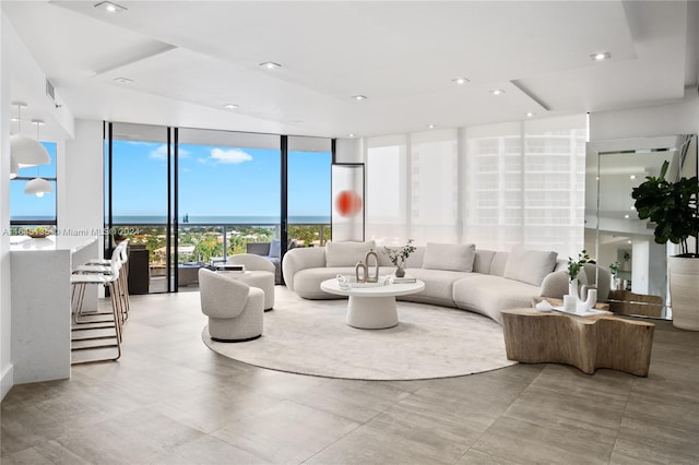 tiled living room with a wealth of natural light, a water view, and floor to ceiling windows