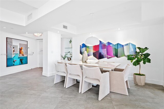 tiled dining space with a raised ceiling