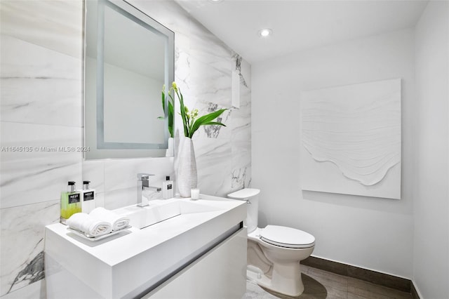 bathroom featuring tile walls, toilet, vanity, and tile patterned floors