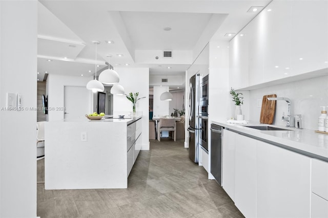 kitchen featuring a tray ceiling, white cabinets, light tile patterned floors, sink, and stainless steel appliances